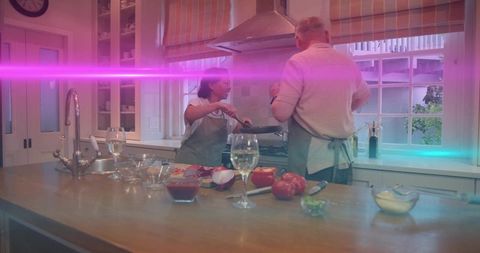 Senior couple cooking together in bright home kitchen with wine and fresh ingredients