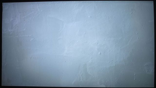 Off-white plaster wall texture showing trowel marks, small pits and subtle vignette