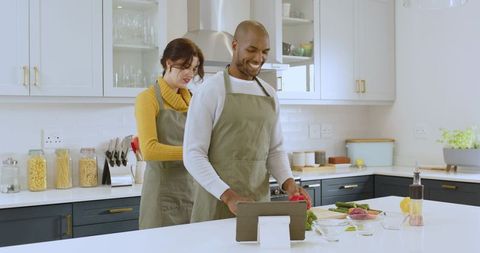Diverse Couple Prepares Meal in Modern Kitchen with Tablet Assistance
