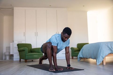 Man Performing Stretching Exercise on Yoga Mat in Cozy Bedroom