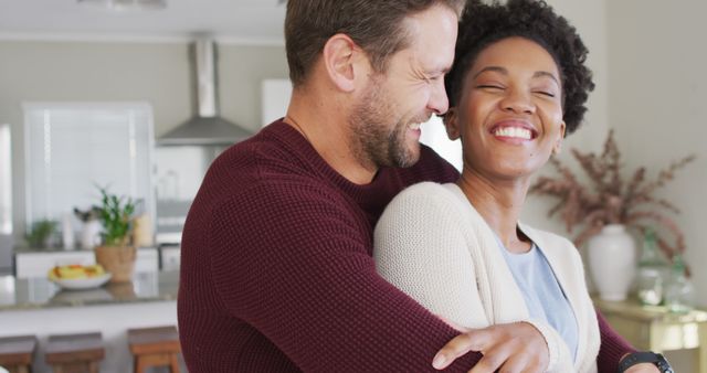 Couple happily embracing and laughing in modern kitchen implies warm and loving relationship. Effective for advertising campaigns on relationships, bonding moments, and home lifestyle. Suitable for blogs and websites promoting happiness, marriage, or family life.