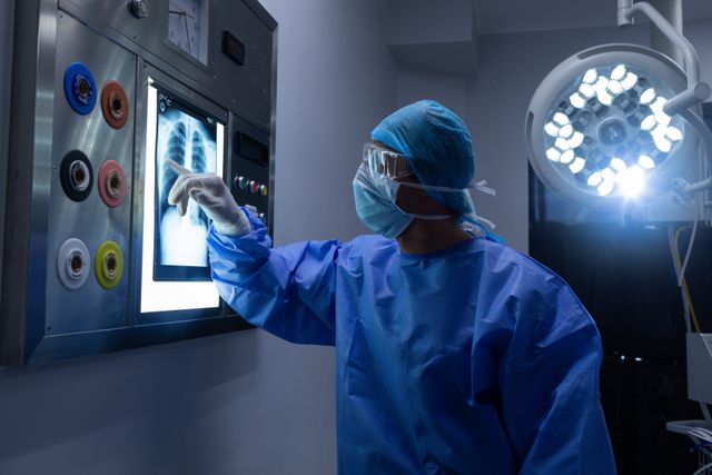 Male surgeon examining x-ray on light box in operation theater at hospital