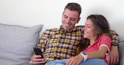 Couple Enjoying Time on Sofa Using Mobile Phone
