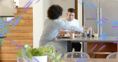 Couple sharing relaxed breakfast at modern kitchen island reaching for French press