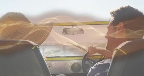 Couple driving convertible along sunlit coastal road wearing straw hat and summer clothes