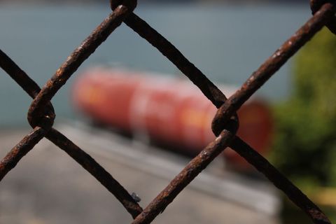 Rusty chain link fence overlooking industrial silos