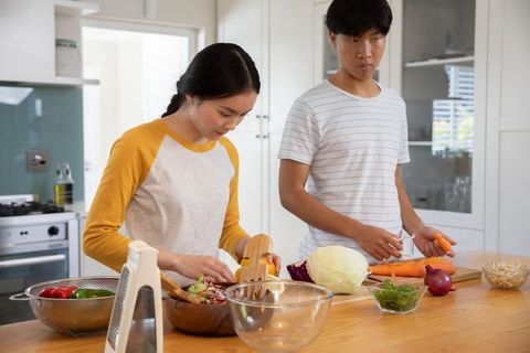Asian Couple Preparing Healthy Vegetable Salad in Modern Kitchen