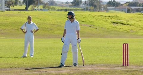 Women Playing Cricket on Lush Field with Pink Stumps