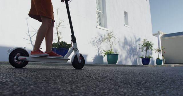 Person on an Electric Scooter Riding Against a White Building - Download Free Stock Images Pikwizard.com