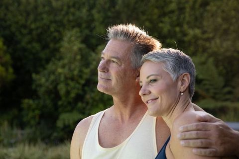 Mature Couple Embracing in Sunlit Garden Setting