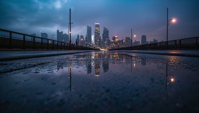 Urban dusk skyline reflection on wet bridge roadway