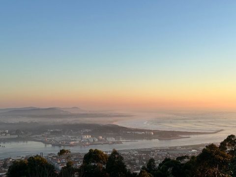 Scenic beach sunset over riverside coastal town with rolling hills