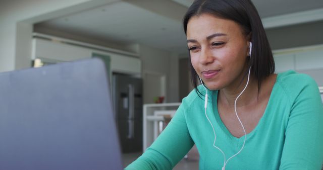 Focused Woman in Green Sweater Using Laptop with Earphones at Home - Download Free Stock Images Pikwizard.com