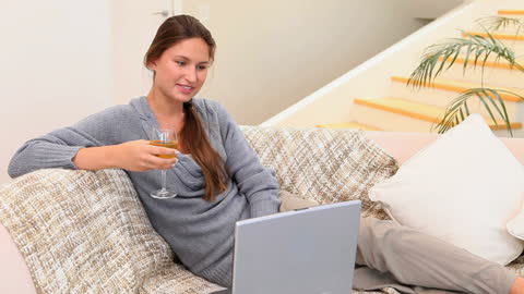 Relaxed Woman Video Calling and Wine Drinking on Sofa