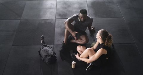 Diverse Workout Partners Relaxing and Chatting in Gym