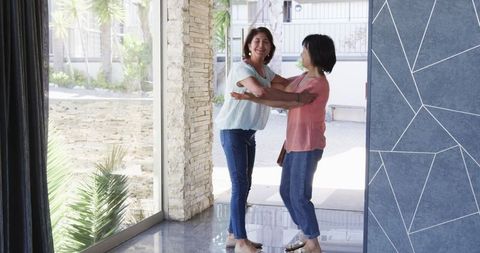Senior Friends Embracing at Front Door, Friendship and Happiness