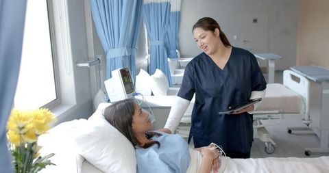 Nurse consulting patient in hospital room with medical equipment