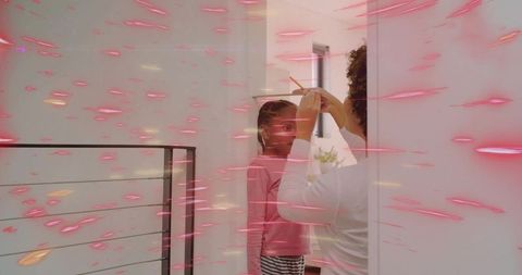 Caregiver adjusting girl's hair in bright hallway with pink light streaks, bonding moment