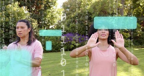 Two women practicing hand-gesture fitness with augmented reality interface in park