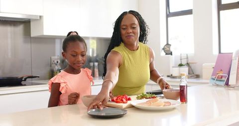 African American Mother and Daughter Preparing Healthy Breakfast in Sunlit Modern Kitchen