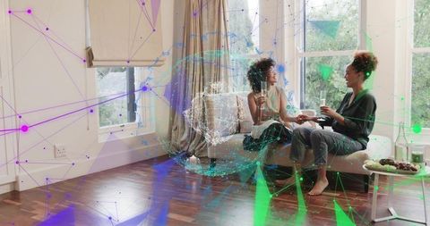 Friends sharing wine on sofa with augmented reality data overlay, cozy home conversation