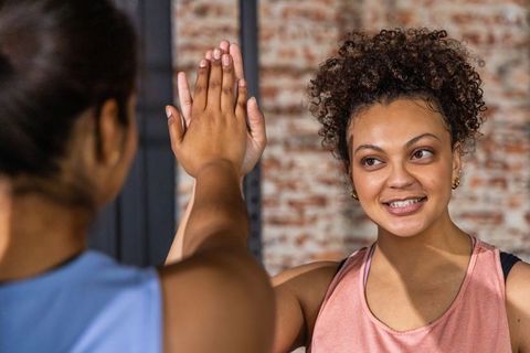 Friends celebrating post-workout high-five in urban gym smiling and motivating each other