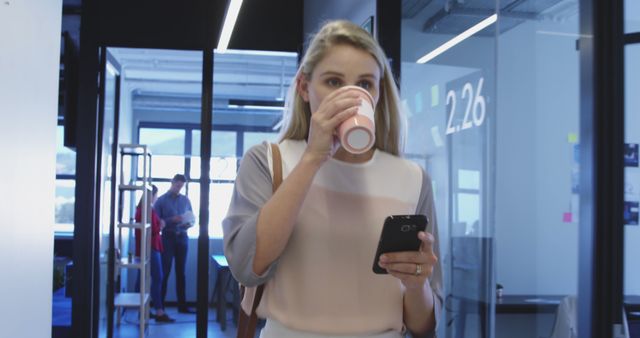 Multitasking Woman Drinking Coffee and Using Smartphone in Office - Download Free Stock Images Pikwizard.com