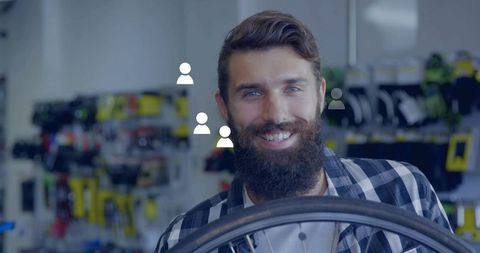 Bearded Mechanic Smiling in Modern Bike Shop Holding Wheel