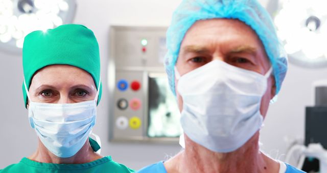 Two surgeons, one male and one female, standing in an operating room wearing surgical masks and scrubs. They are prepared for surgery with surgical lights in the background. Useful for illustrating concepts of surgery, healthcare, medical teamwork, and hospital environments.