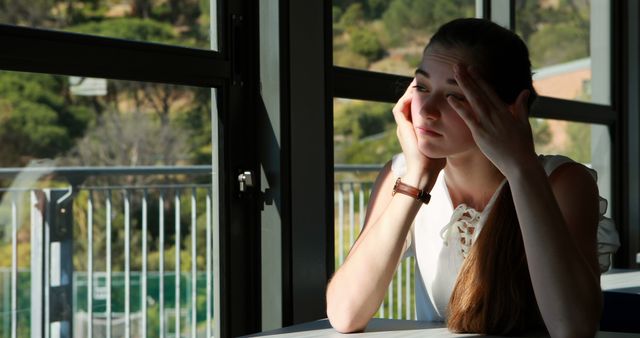 Pensive Young Woman Sitting by Window in Sunlit Room - Download Free Stock Images Pikwizard.com