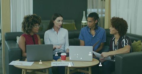 Young professionals collaborating over laptops in cozy lounge brainstorming project ideas