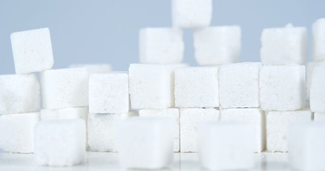 Stacked white sugar cubes creating an abstract arrangement on a light background. Ideal for illustrating concepts related to baking ingredients, sweeteners, dietary topics, food additives, and nutrition discussions. Perfect for use in websites, blogs, dietary guides, health articles, and educational materials.