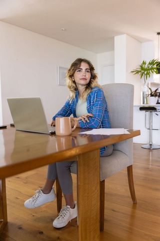 Woman working at home with laptop and coffee in cozy environment