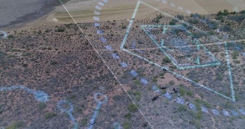 Aerial drone projecting futuristic blue hud overlays over semiarid scrubland and farmland