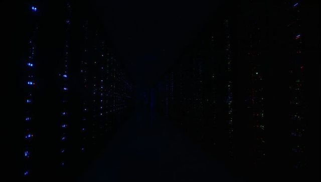 Glowing server racks lining dark data center aisle with blinking led lights and cables