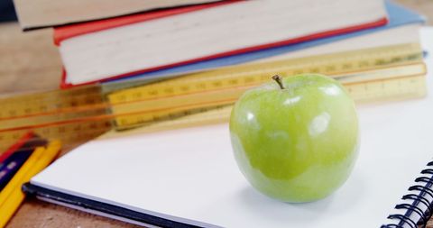 Green apple with school supplies symbolizing health and education