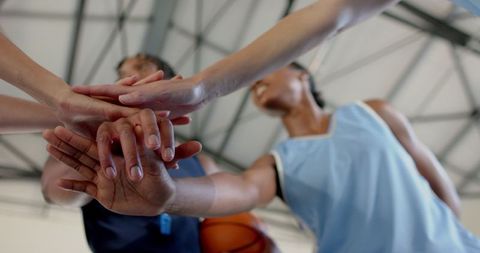 Basketball Teammates Showing Unity with Hands Stacked on Court