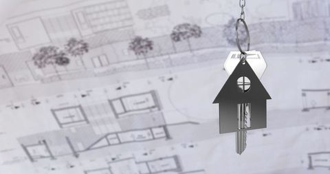 House-shaped keychain hanging over architectural blueprints