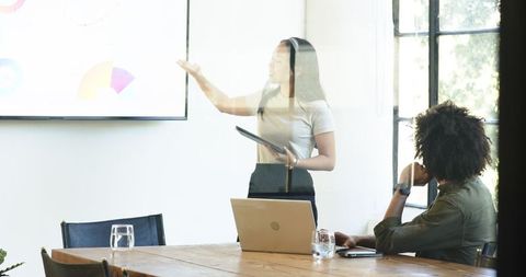 Businesswoman Presenting with Tablet and Charts for Team Meeting