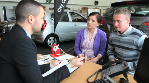 Dealership Consultant Explaining Details to Prospective Car Buyers