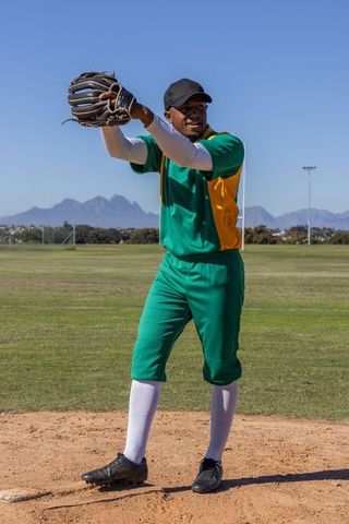 African American Baseball Pitcher Delivering Pitch on Sunny Field with Distant Mountains