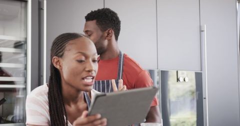 Couple exploring recipe on tablet in modern kitchen