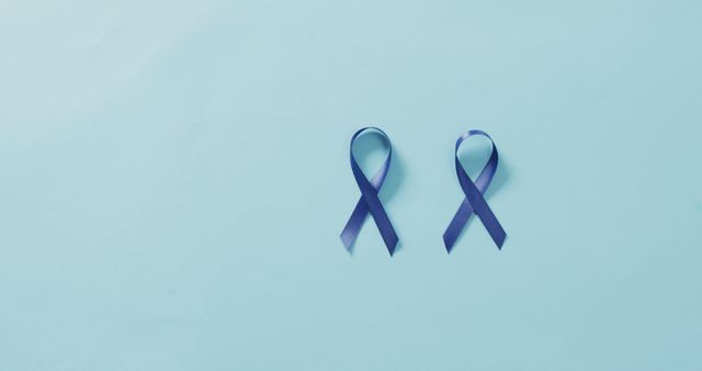 Image of two dark blue colon cancer ribbons on pale blue background. medical and healthcare awareness support campaign symbol for colon cancer.