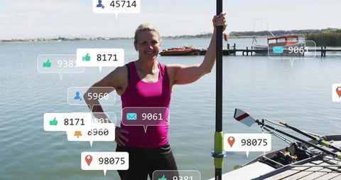 Mature female rower posing on dock with oar and social media icons for fitness lifestyle