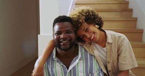 Diverse Couple Embracing on Home Stairs with Warm Smiles