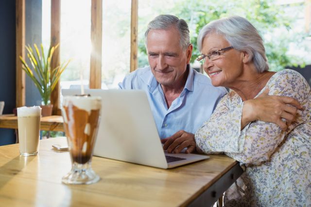 Senior couple using laptop in cafÃ©