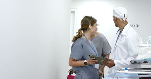 African american doctor collaborating with nursing team in hospital corridor holding tablet