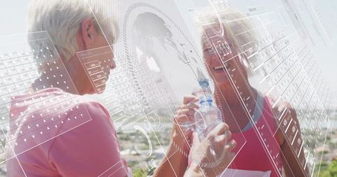 Senior runner receiving support during outdoor run, friend offering water, smiling fitness duo