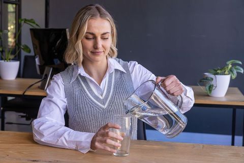 Professional woman pouring water in modern office environment