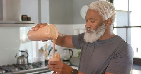 Senior African American Man Pouring Healthy Smoothie in Modern Kitchen